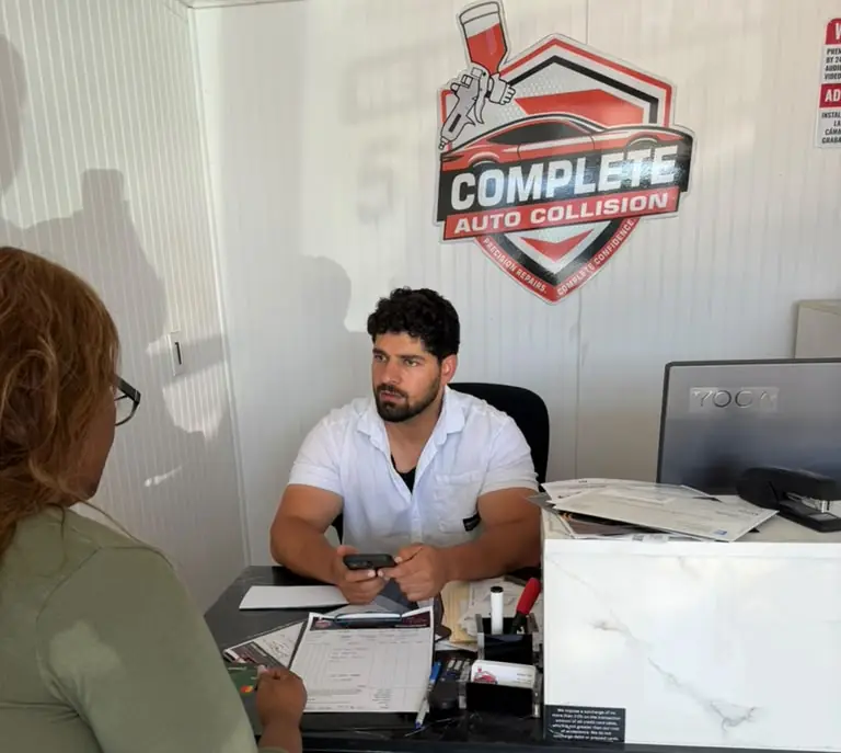 Front desk at Complete Auto Collision with the shop logo on the wall