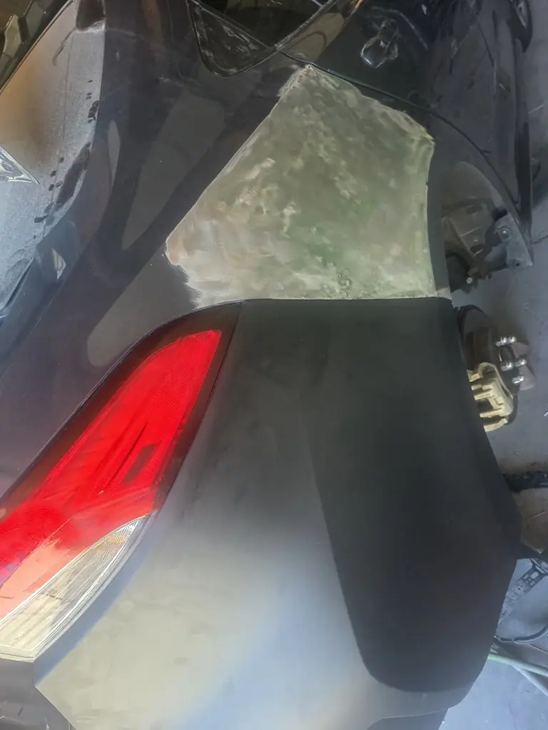 Body filler shaped next to a taillight during panel repair