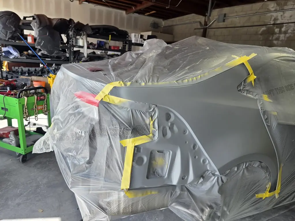 Car masked in plastic and tape in the shop bay, ready for paint