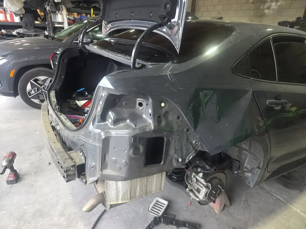 Crushed rear quarter panel with the trunk open during tear-down